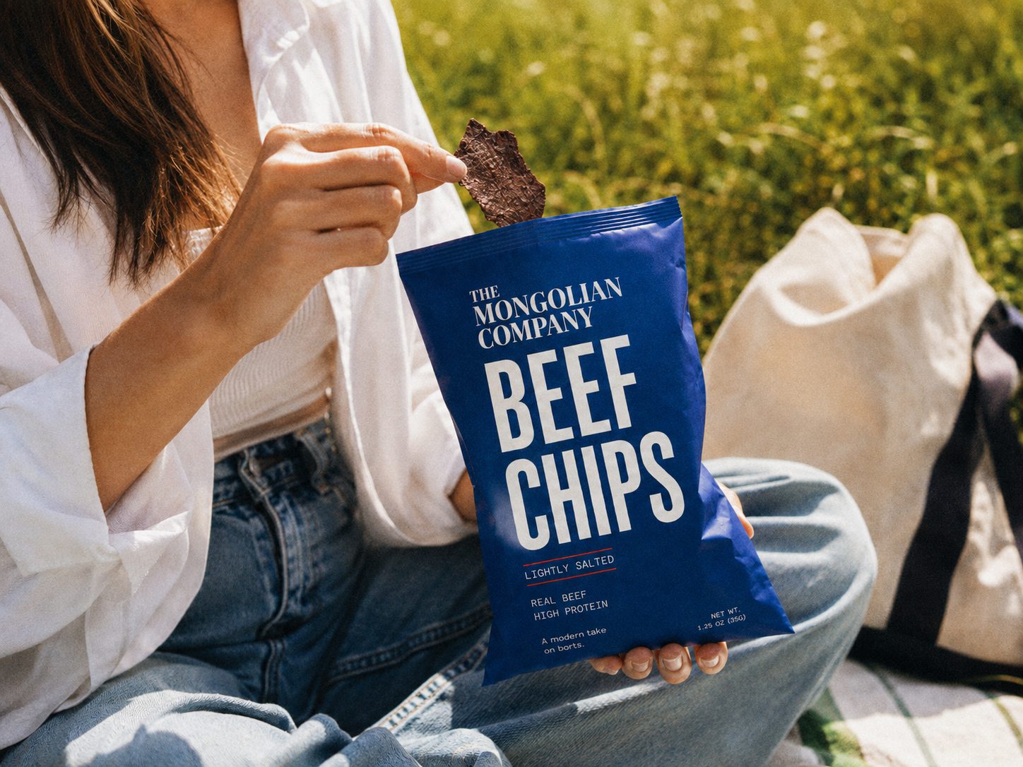 A person eating The Mongolian Company Beef Chips outdoors